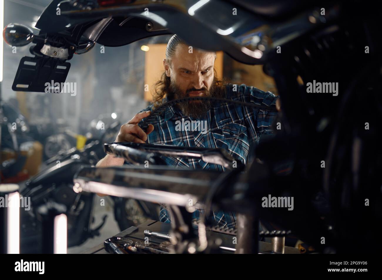 Hombre motociclista o mecánico que fija el motor de motociclo que trabaja en el garaje Foto de stock