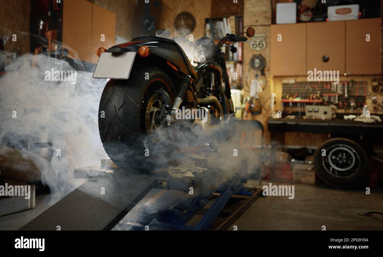 Motocicleta en nubes de humo de pie en el garaje de motociclistas o motociclistas Foto de stock