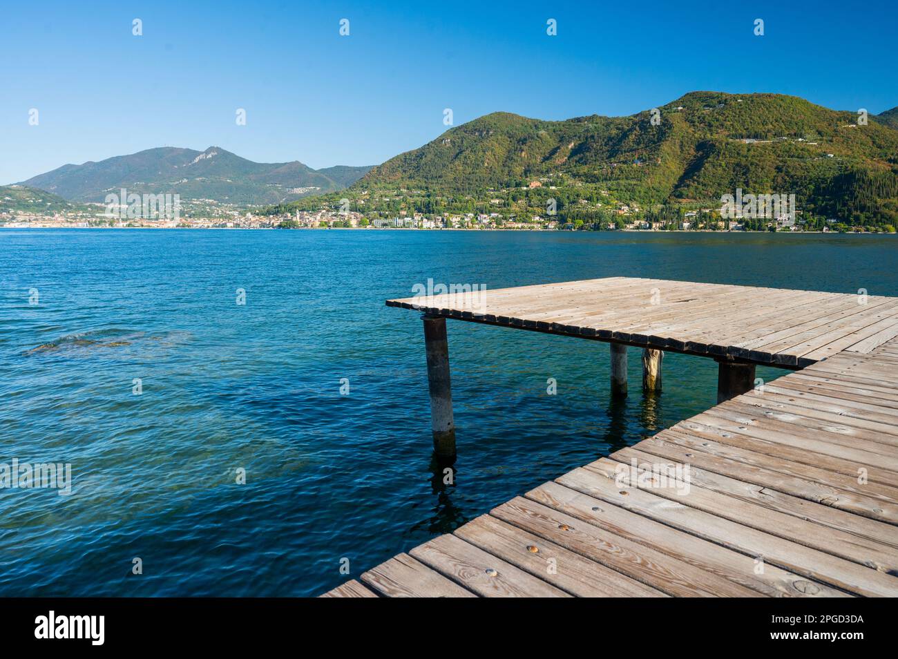 Embarcadero o embarcadero en las aguas claras del lago de Garda Foto de stock