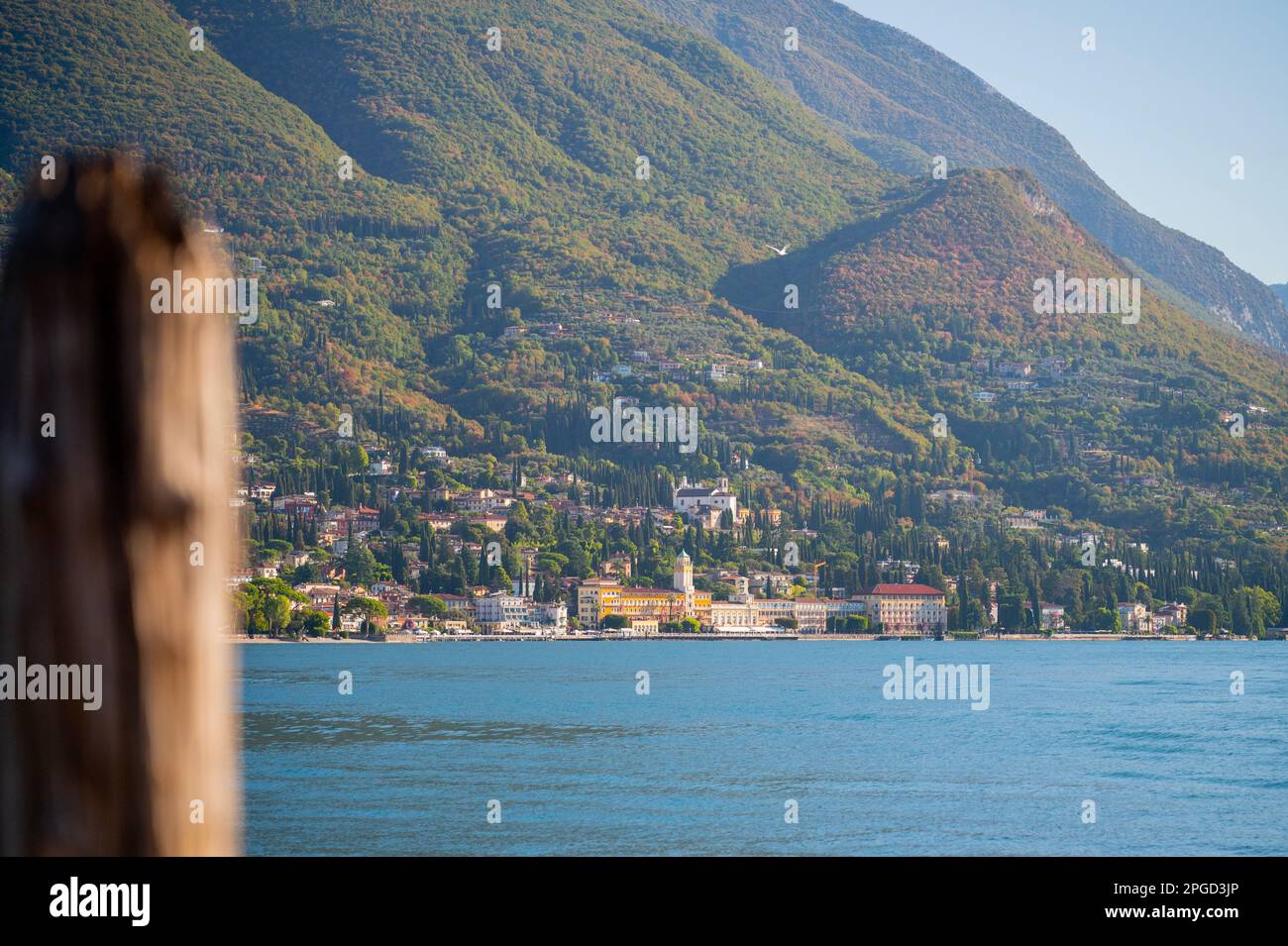 Lago de Garda en Italia, agua azul bajo un cielo azul con barcos en primer plano y montañas que rodean el lago Foto de stock