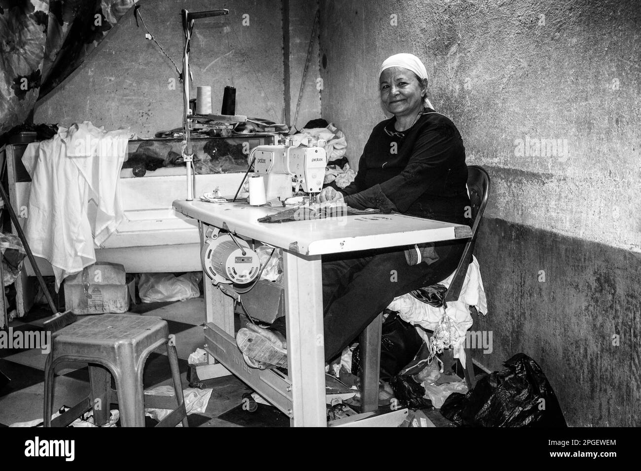 Una mujer cosiendo en su tienda de sastrería en Luxor, Egipto. Foto de stock