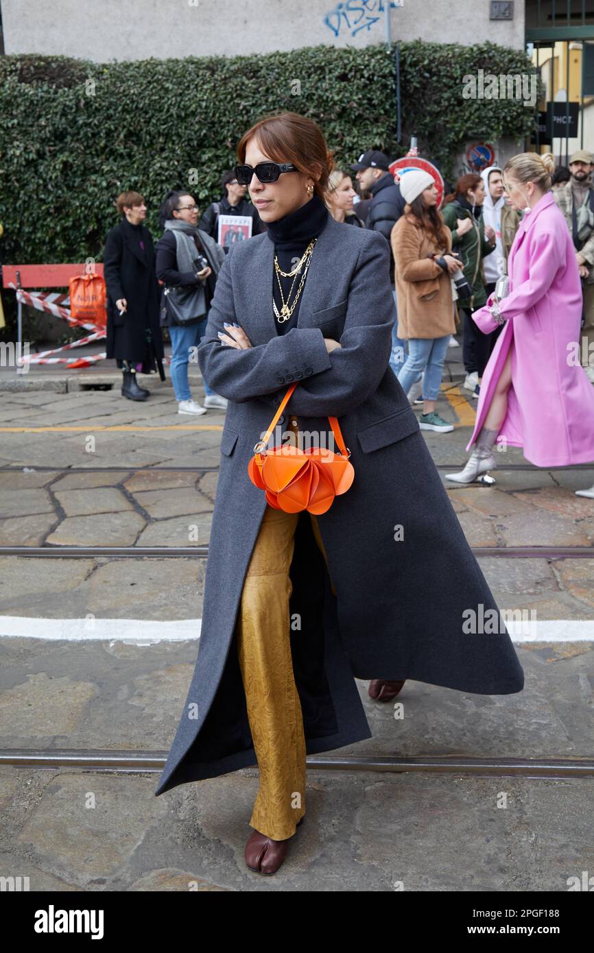 MILÁN, ITALIA - 24 DE FEBRERO de 2023: Mujer con abrigo gris y bolso naranja antes del desfile Sportmax, estilo callejero de la Semana de la Moda de Milán Foto de stock