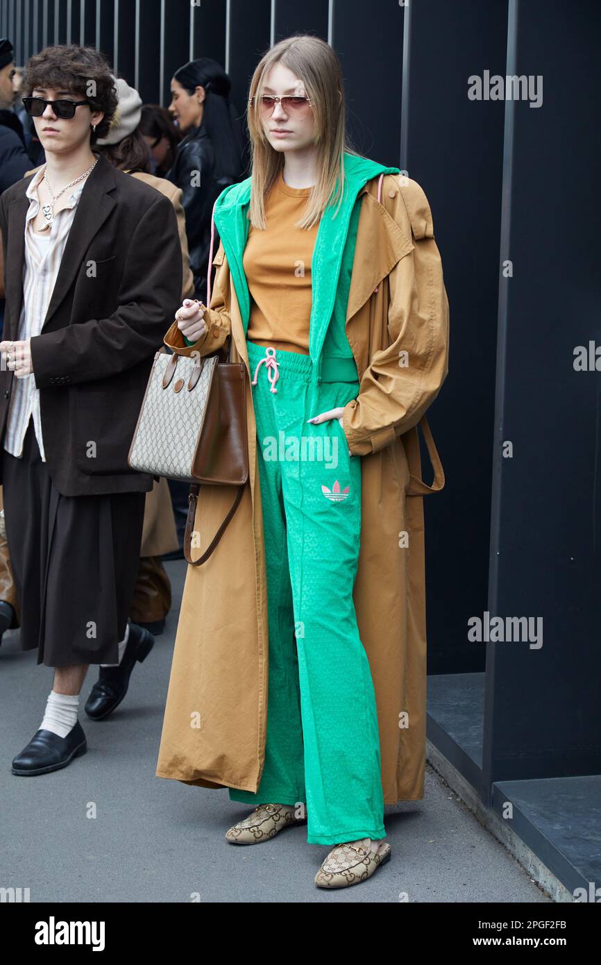MILÁN, ITALIA - 24 DE FEBRERO de 2023: Mujer con pantalones y chaqueta  Adidas verdes y gabardina beige antes del desfile de Gucci, Milan Fashion  Week stre Fotografía de stock - Alamy