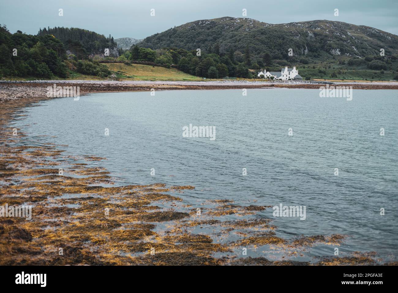 Vista de la hermosa bahía escocesa y la casa antigua con las tierras altas Foto de stock
