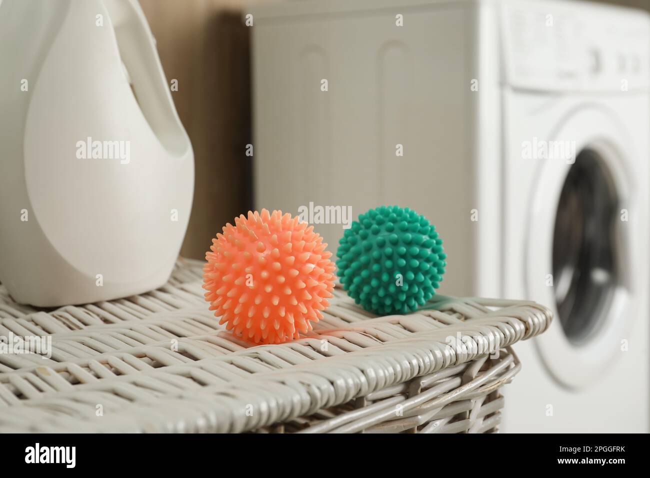 Secador de bolas y detergente ropa en la cesta de mimbre cerca de la lavadora, primer plano Fotografía de stock