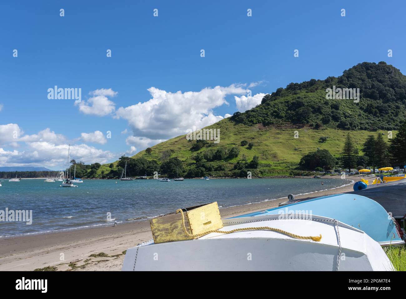 Bote volteado y caja amarilla y cuerda en la costa del Monte Maunganui de Pilot Bay Foto de stock