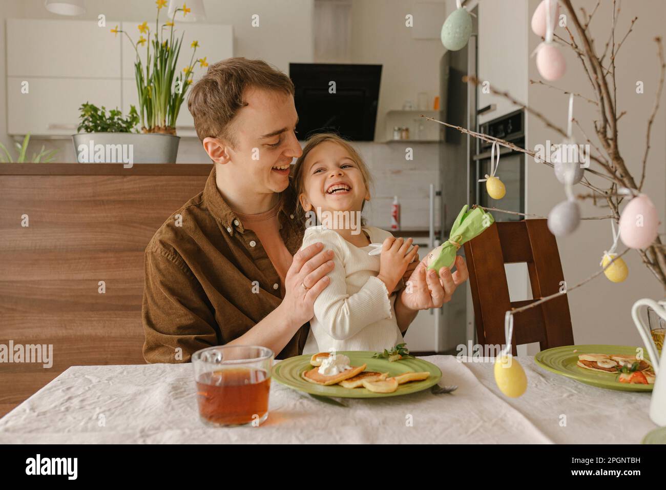 Padre e hija felices con comida de Pascua en la mesa Foto de stock