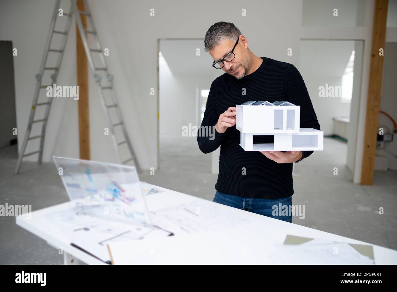 Diseño profesional examinando casa modelo en el sitio de construcción Foto de stock
