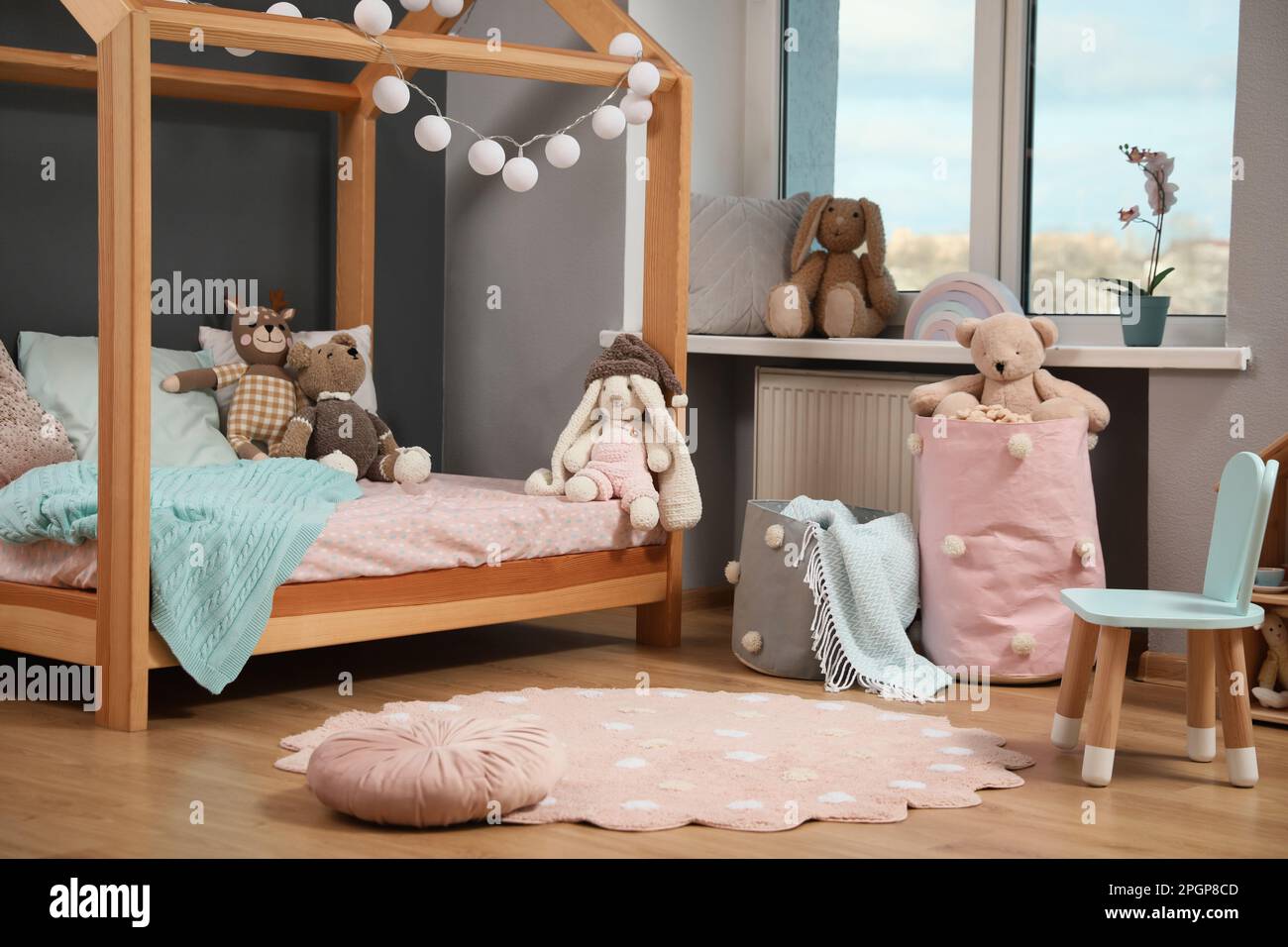 Elegante interior de la habitación infantil con cama de madera en forma de  casa y juguetes Fotografía de stock - Alamy