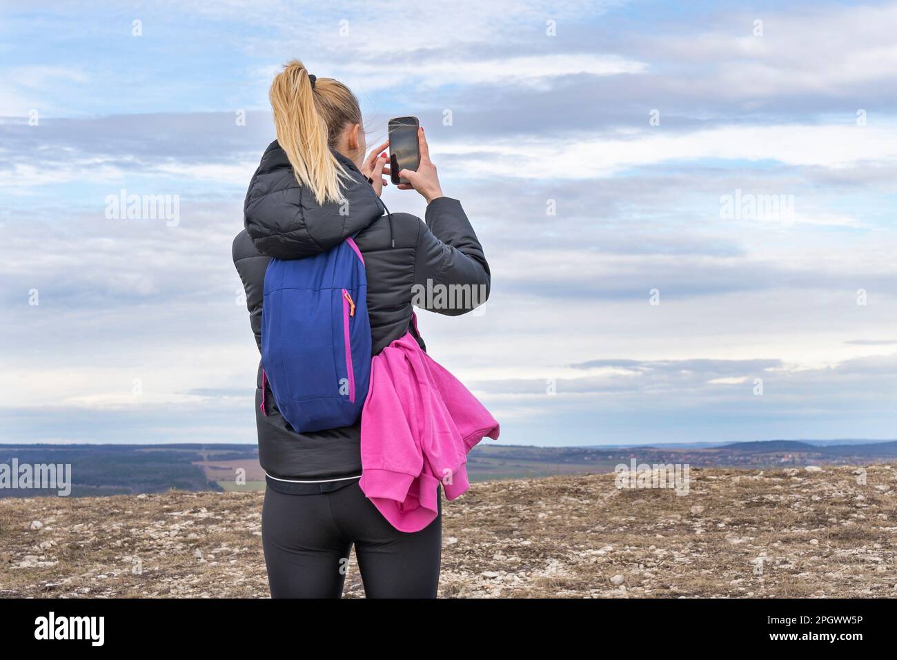 Mujer rubia joven deportiva que fotografía el paisaje con el teléfono móvil Foto de stock