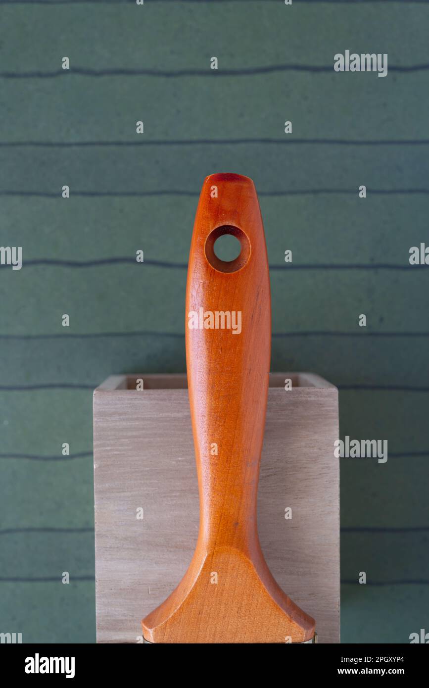 mango de cepillo de pintura de madera clásico en una caja de madera contra un fondo de papel decorativo de scrapbook Foto de stock