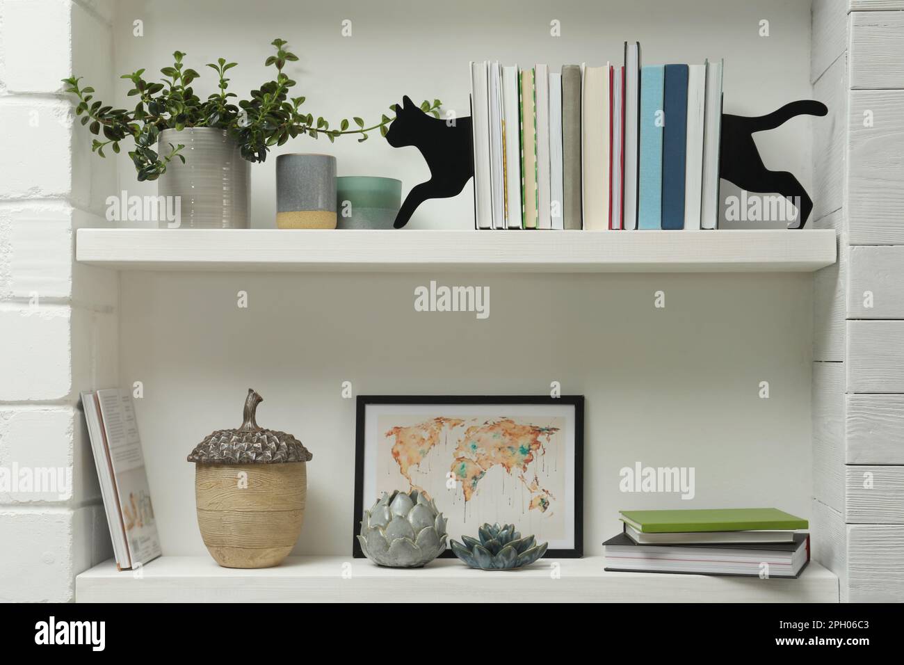 Sujetalibros en forma de gato con libros y decoración diferente en estantes  en el interior. Diseño de interiores Fotografía de stock - Alamy