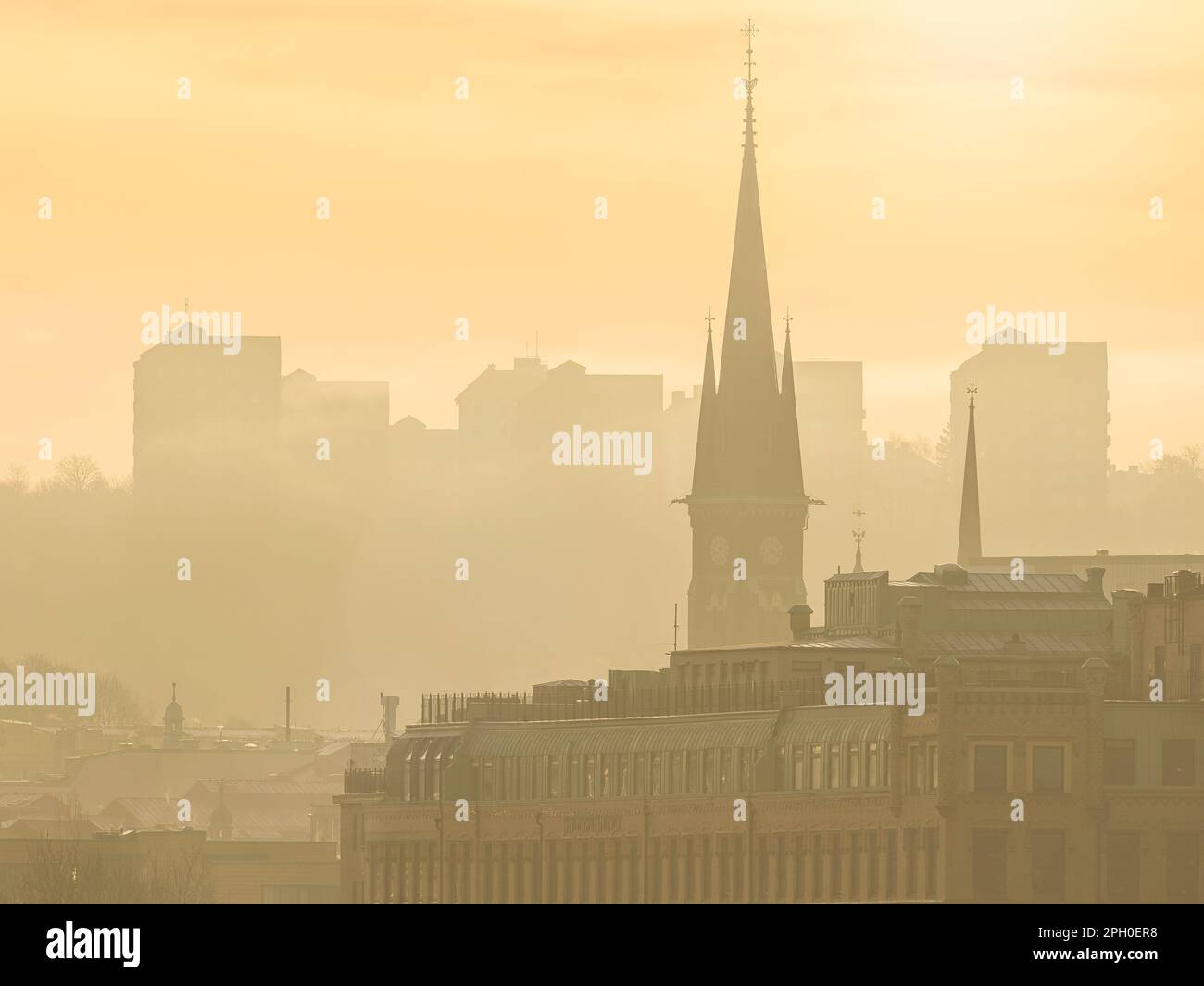 El cielo matutino nebuloso revela el horizonte de Gothenburgs de un paisaje urbano extenso, sus estructuras construidas y las grandes torres de la iglesia que emergen de la neblina. Foto de stock