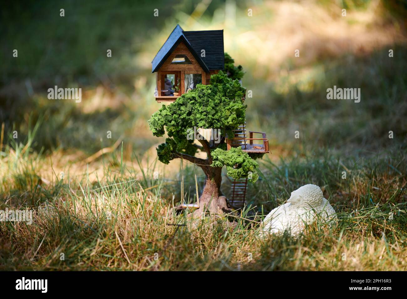 Pequeña casa de muñecas en el césped frontal, pequeña casa decorativa linda  en campo de hierba verde, concepto del medio ambiente. Bosque pequeña casa  de muñecas en hierba verde, charmin Fotografía de