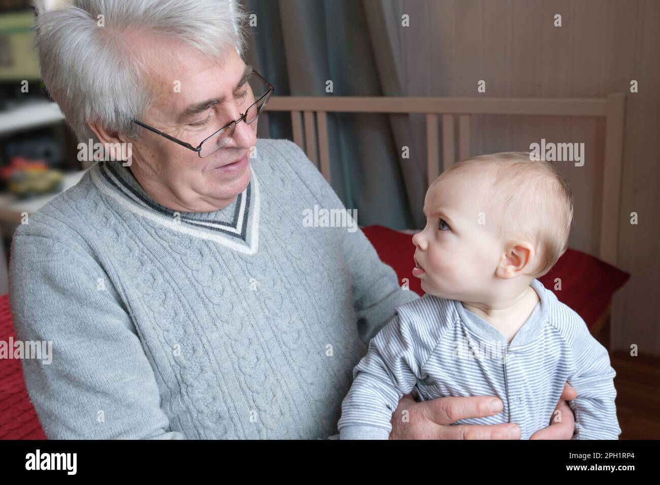 Relaciones familiares de ancianos 60s Hombres y niñas. El hombre viejo feliz sostiene a un niño pequeño en las manos. Abrazo suave y Amor para nieto caucásico en Lenta Foto de stock