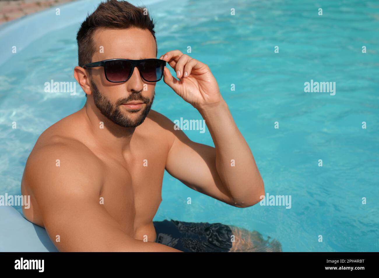 Complejo de piscina. hombre guapo en vacaciones de verano. hombre con gafas  de sol relajándose en la piscina.