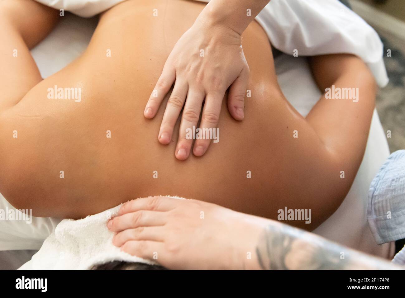 Las manos curativas del terapeuta de masaje alivian el derrame cerebral en los músculos fatigados del cuerpo del paciente. Foto de stock