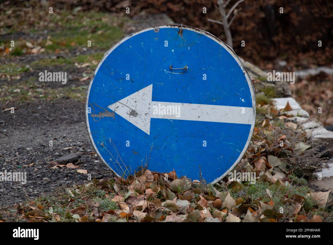 la señal de giro a la izquierda está en la carretera en otoño sin un pilar en el suelo, señal de carretera Foto de stock