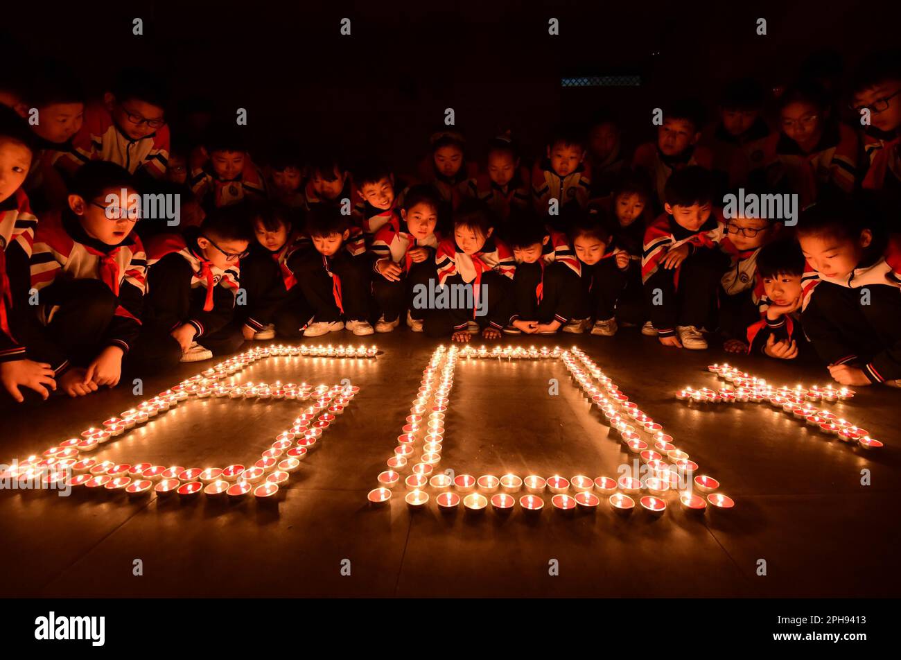 Los estudiantes hacen las palabras '60' con velas para dar la bienvenida al  evento 'Hora de la Tierra' en la ciudad de Handan, provincia de Hebei, al  norte de China, 24 de