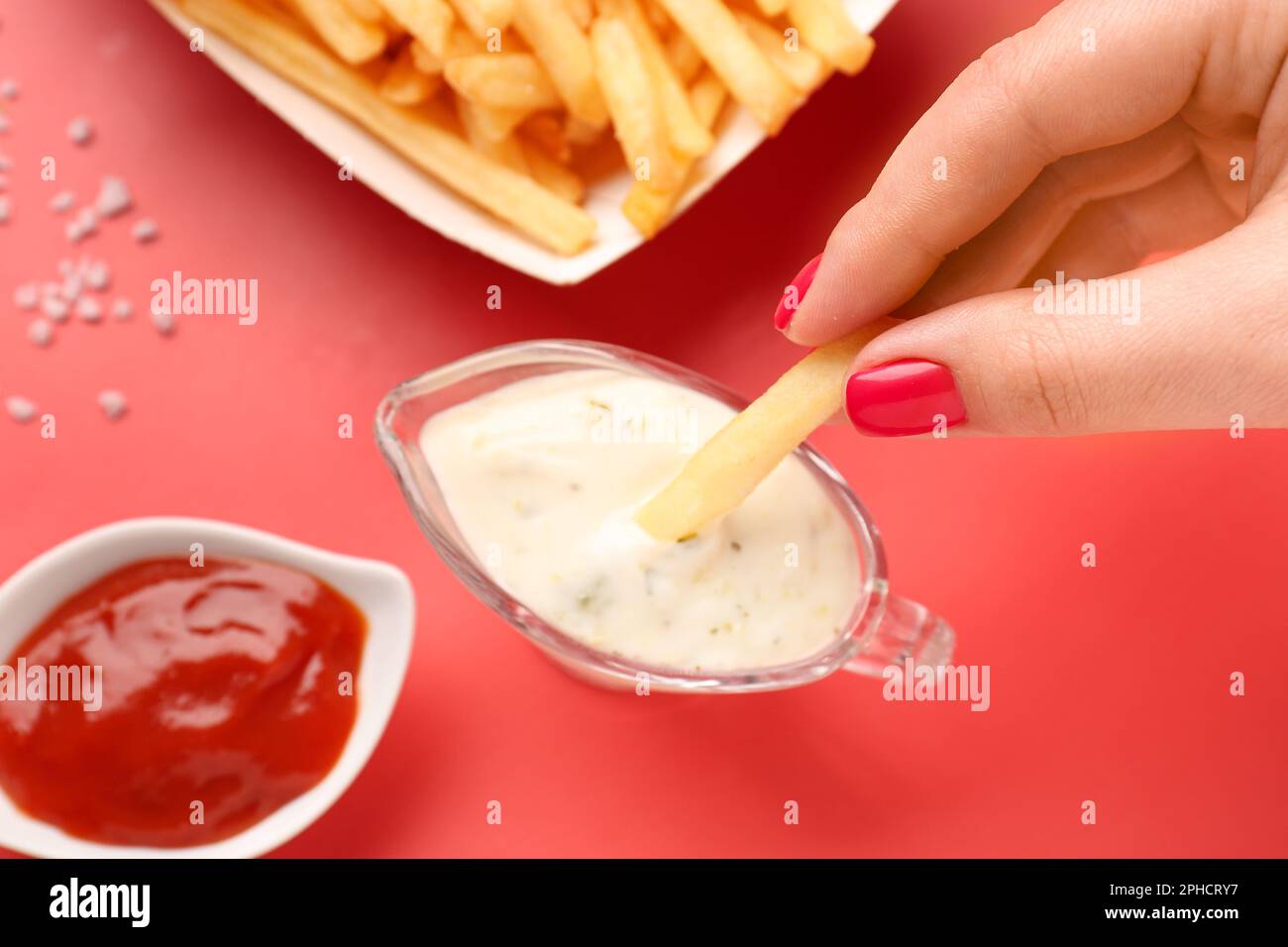Mujer sumergiendo papas fritas en mayonesa sobre fondo rojo Fotografía de  stock - Alamy