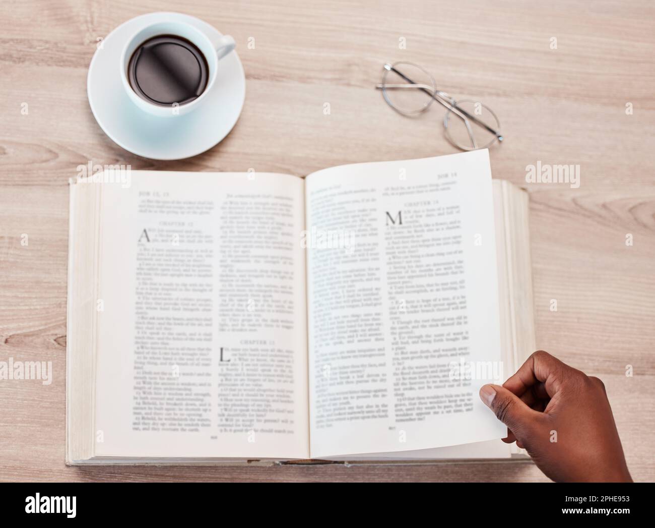 Mano, biblia y una persona leyendo en una cafetería para la religión