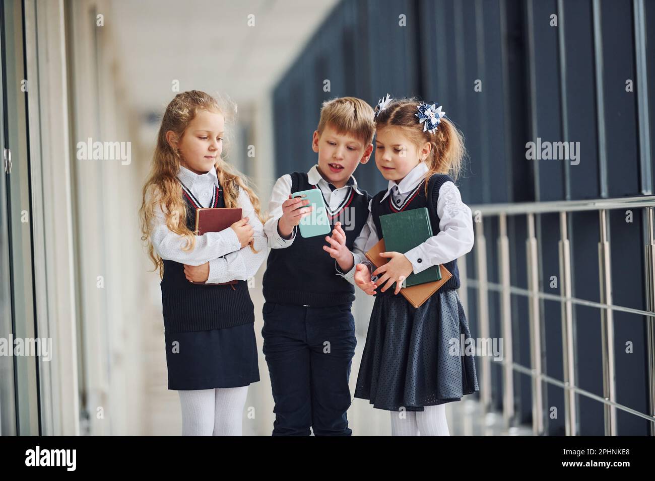 Niños de la escuela en uniforme junto con el teléfono en el pasillo.  Concepción de la educación Fotografía de stock - Alamy