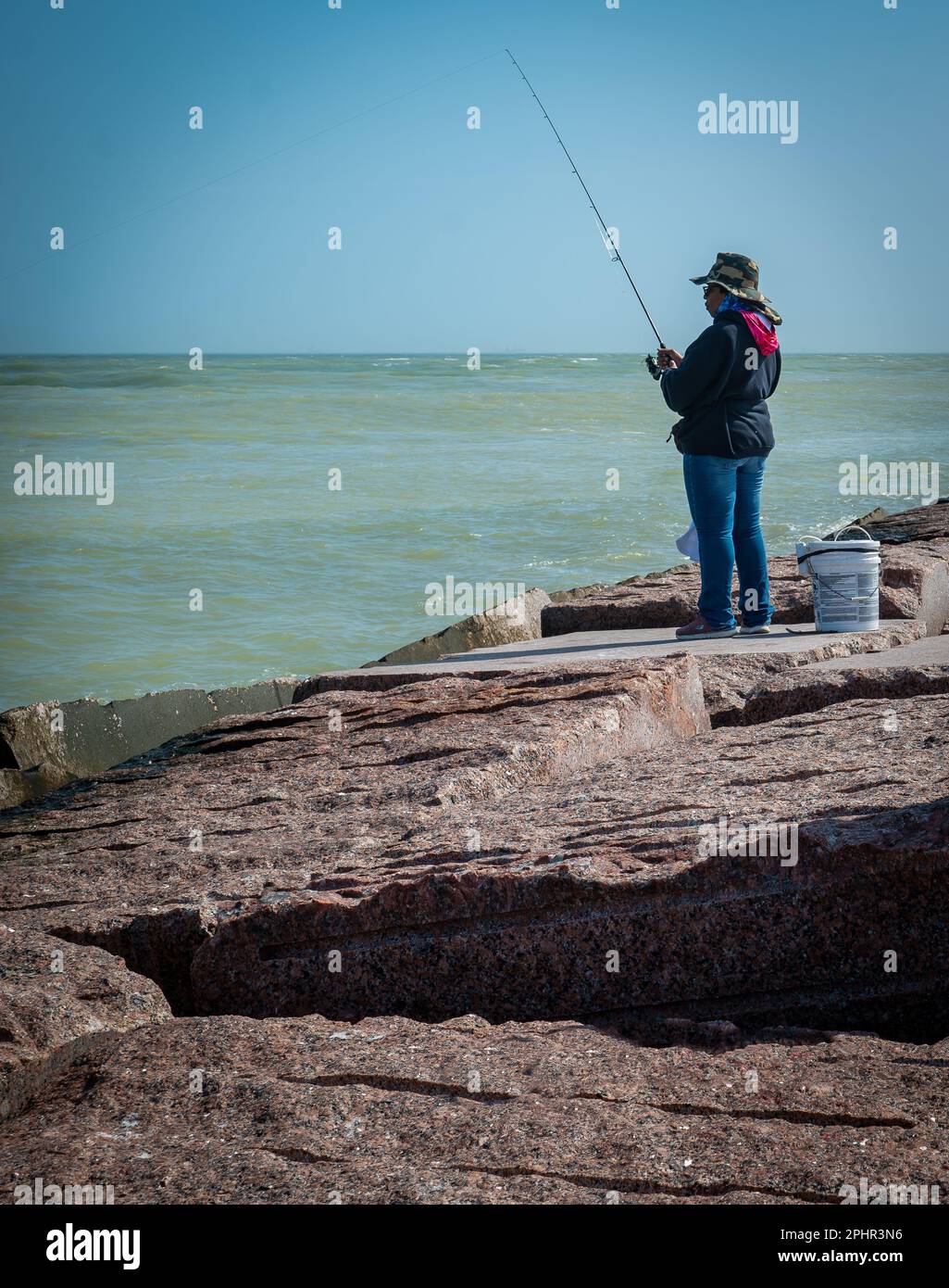 PORT ARANSAS, TX – 7 DE FEBRERO de 2023: Mujer pescando sombrero en el South Jetty en Port Aransas, Texas. Foto de stock