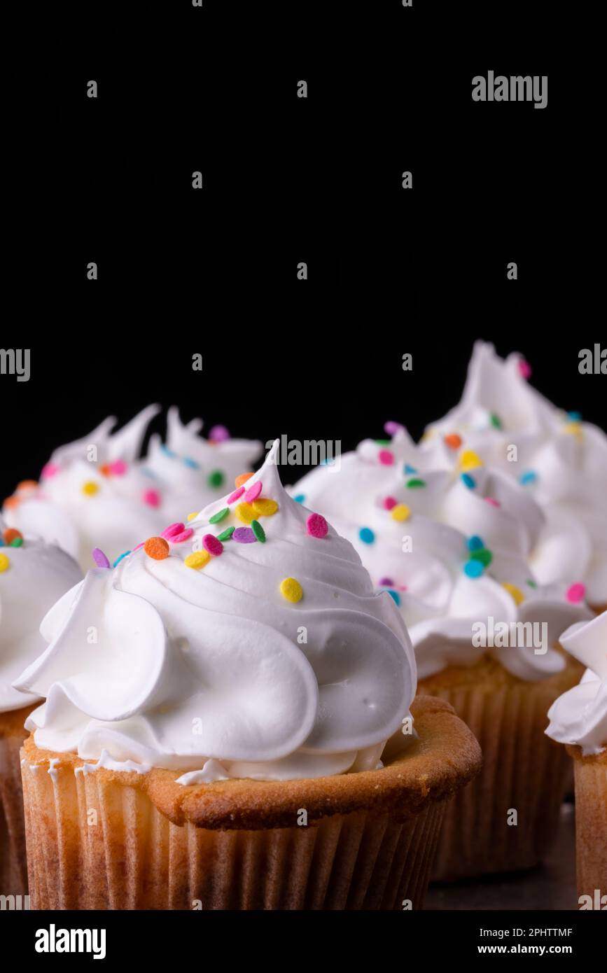 Cupcakes de vainilla esponjosos, con merengue y dragees sobre un fondo