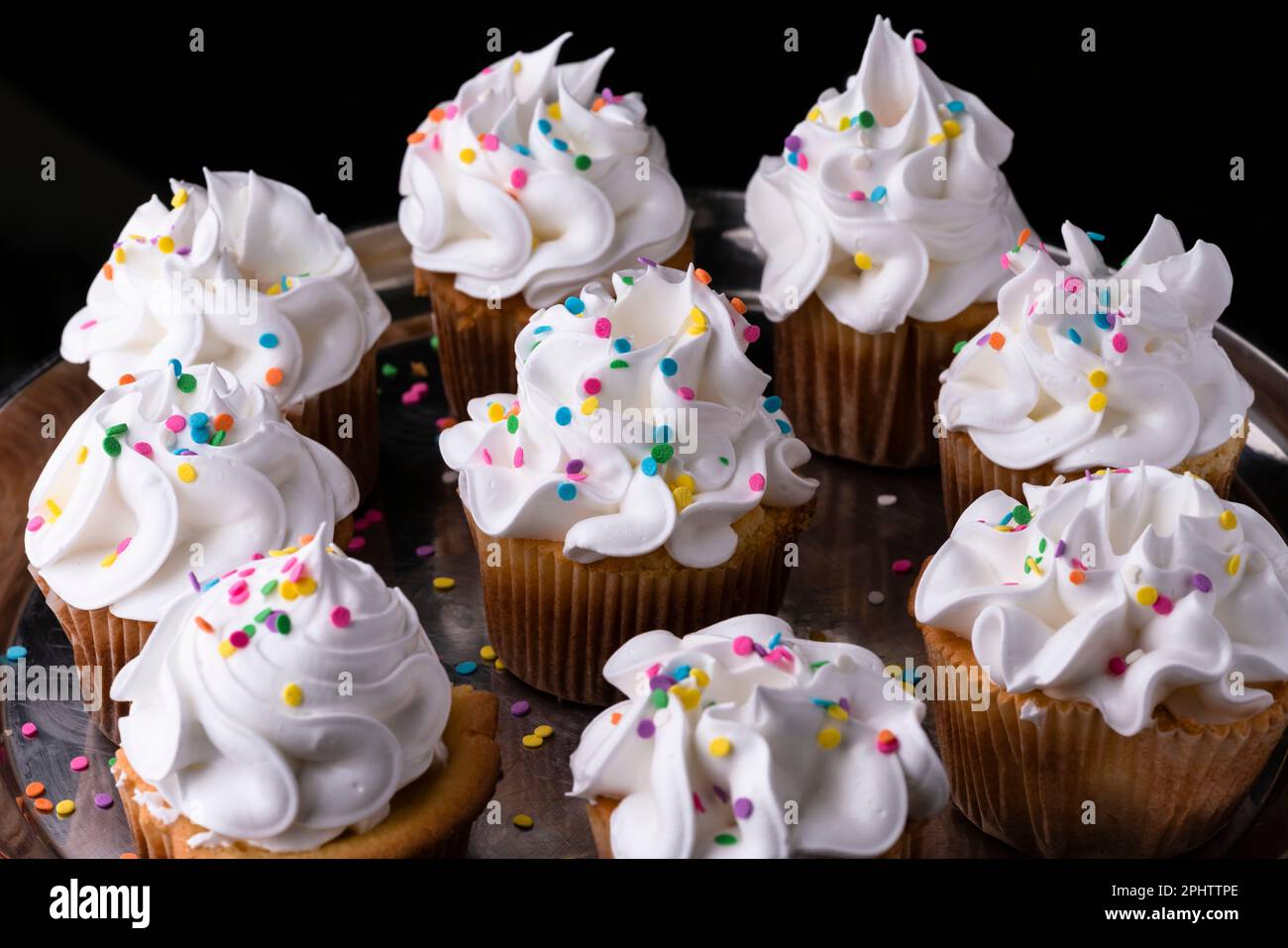 Cupcakes de vainilla esponjosos, con merengue y dragees sobre un fondo