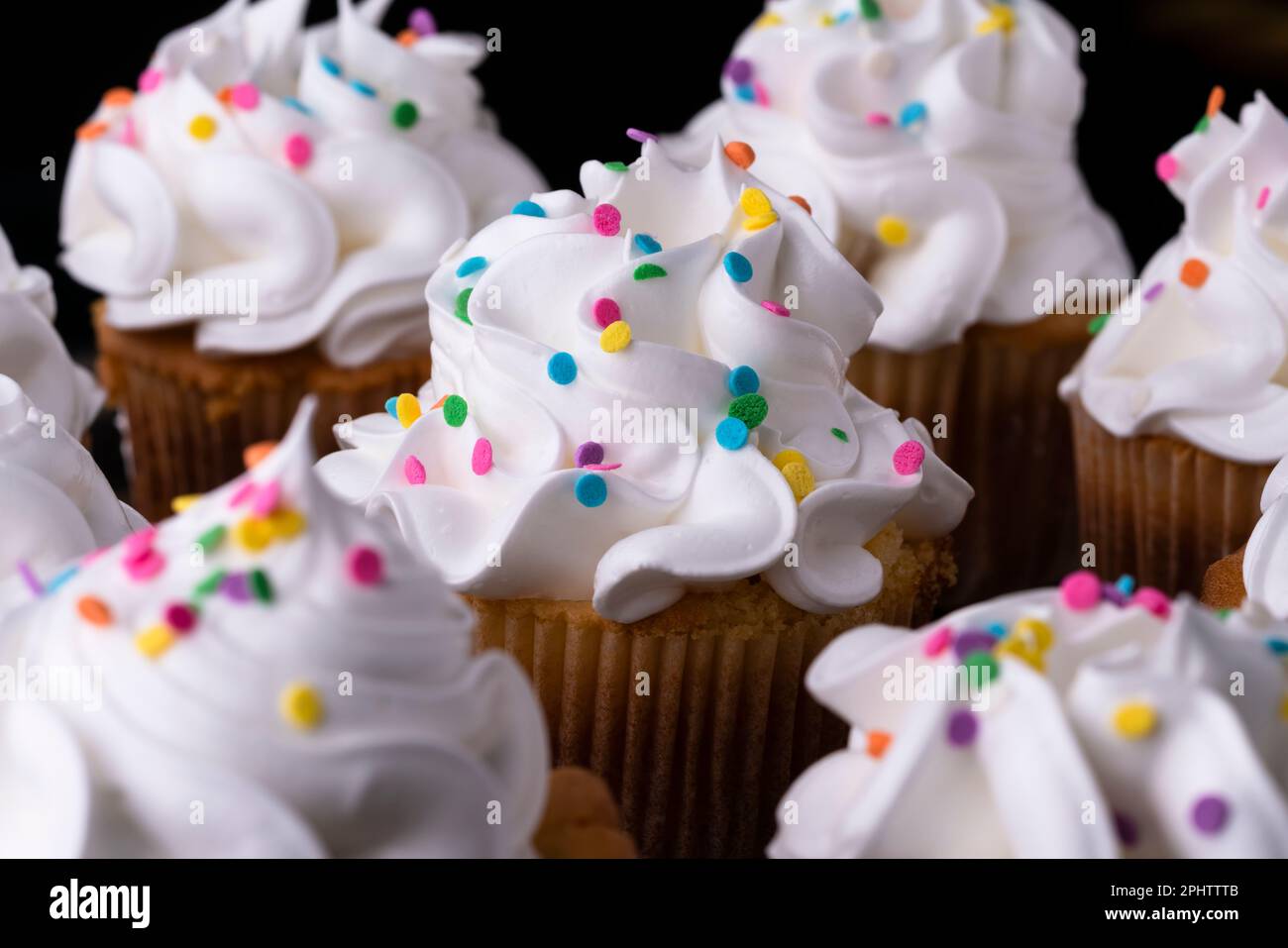 Cupcakes de vainilla esponjosos, con merengue y dragees sobre un fondo