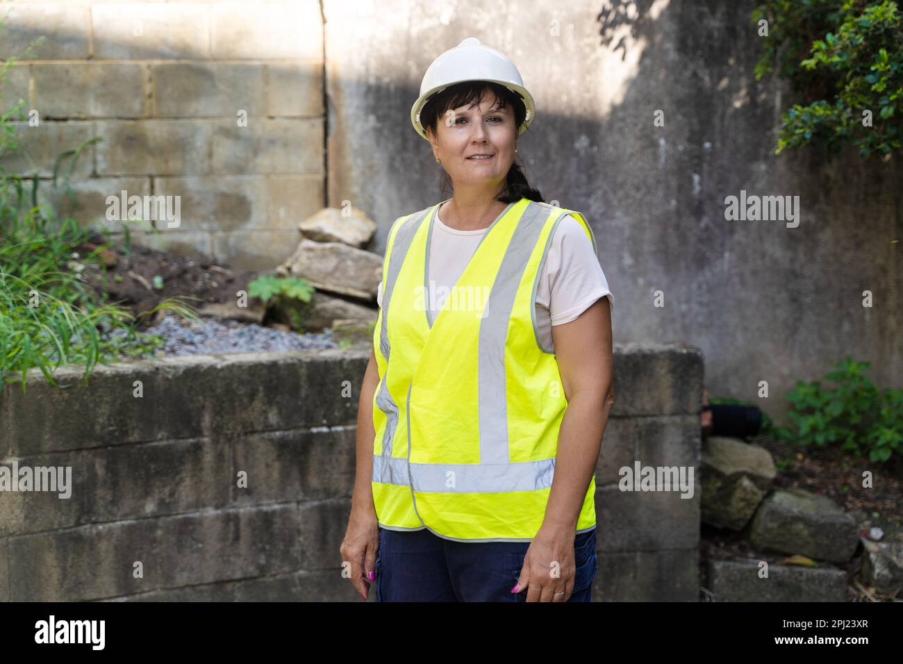 Mujer trabajadora industrial madura. Carretera, sitio de construcción, residuos Foto de stock