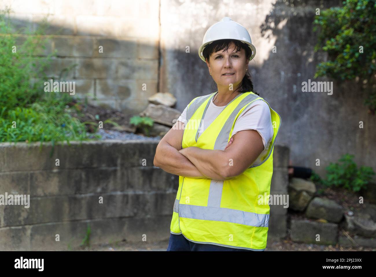 Mujer trabajadora industrial madura. Carretera, sitio de construcción, residuos Foto de stock