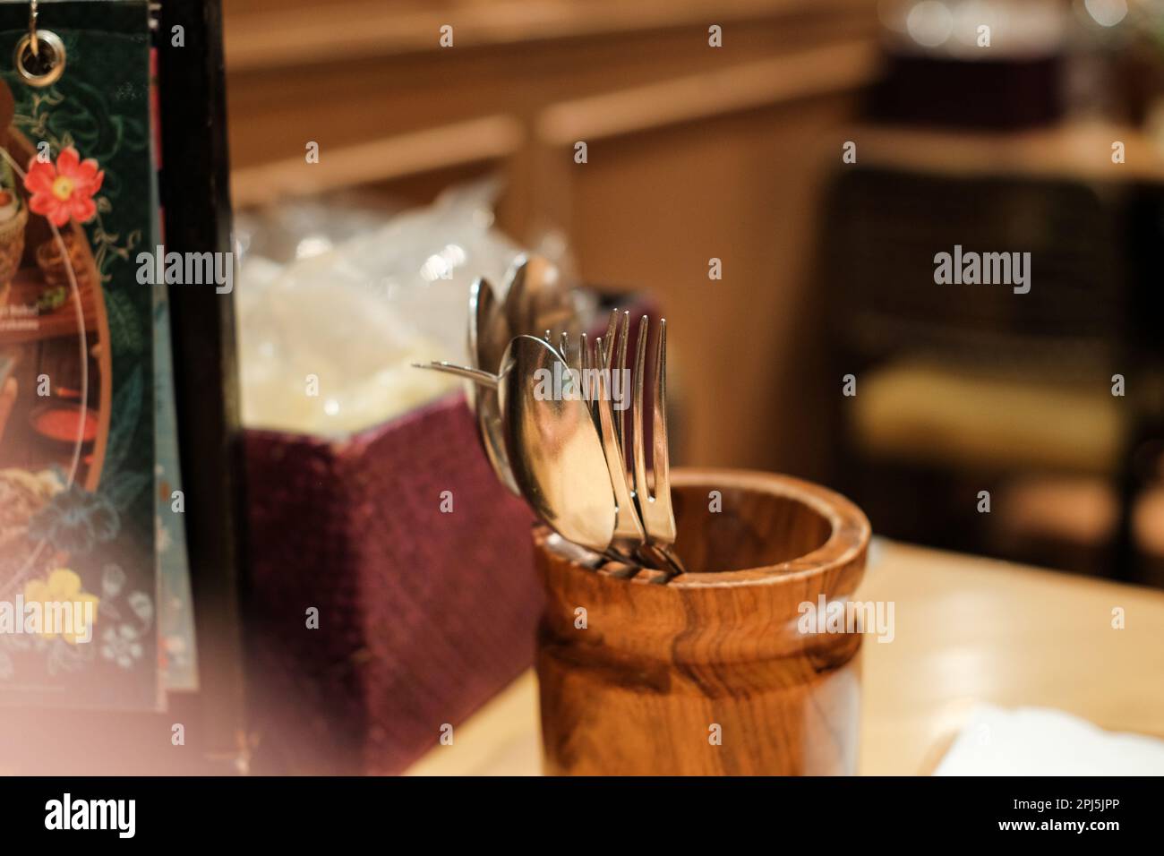Elegante cubertería de madera con tenedores y cucharas. en una mesa en un restaurante de lujo con luz incandescente. Look vintage y retro. Foto de stock