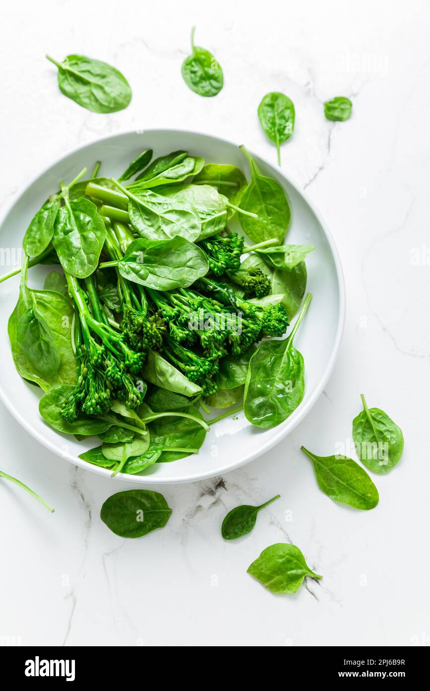 Espinaca orgánica con broccolini (bimi) en tazón sobre fondo blanco Foto de stock