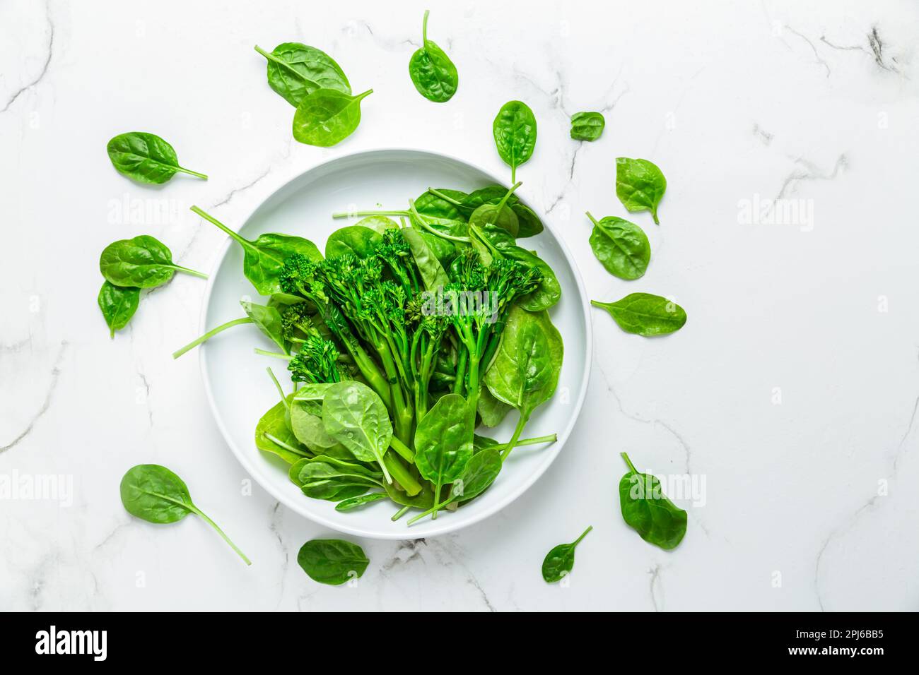Espinaca orgánica con broccolini (bimi) en tazón sobre fondo blanco Foto de stock