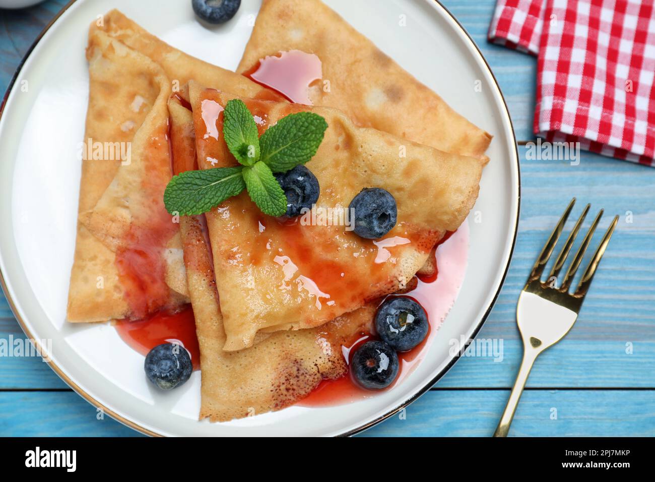 Deliciosos crepes servidos con arándanos, menta y jarabe en mesa de madera  azul, plano Fotografía de stock - Alamy