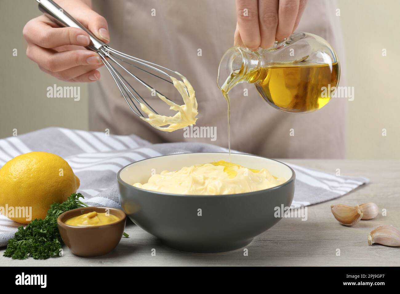 Mujer haciendo mayonesa casera en tazón de cerámica en la mesa de