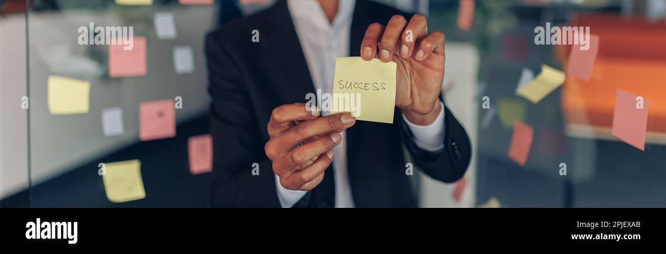 Hombre de negocios africano mostrando notas pegajosas con frases motivadoras  mientras estaba de pie en la oficina Fotografía de stock - Alamy