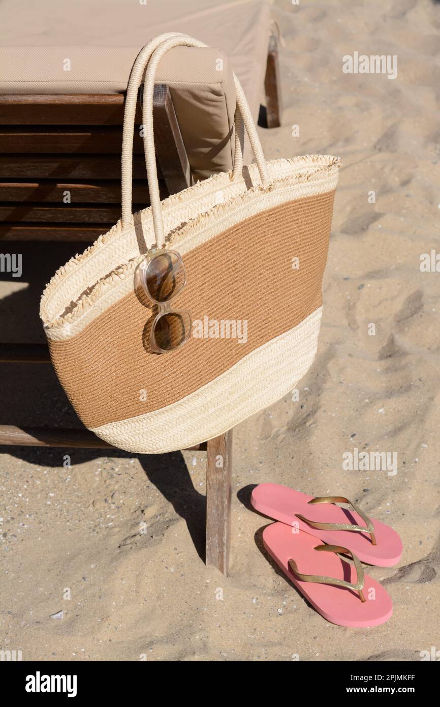 Bolso de paja con gafas de sol y chanclas en la arena. Accesorios de playa  Fotografía de stock - Alamy