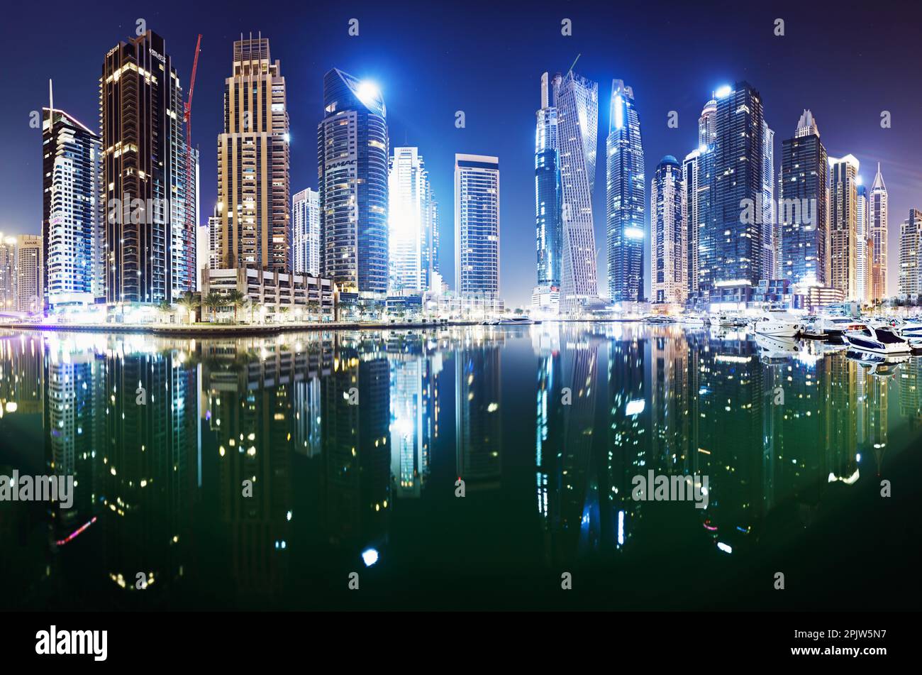 Paseo marítimo y canal en Dubai Marina por la noche con rascacielos de lujo alrededor, Emiratos Árabes Unidos Foto de stock