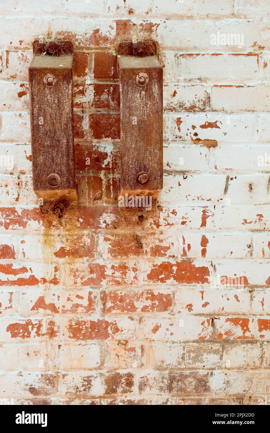 Soportes de hierro oxidado con telas de araña en la pared de ladrillo lavado blanco. Foto de stock