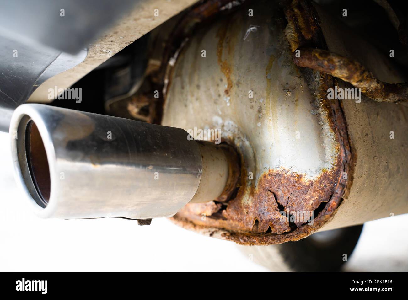 Silenciador de escape de coche oxidado con un orificio pasante, primer plano. Corrosión en un tubo de escape metálico después del invierno. La reacción de sales y reactivos en invierno Foto de stock
