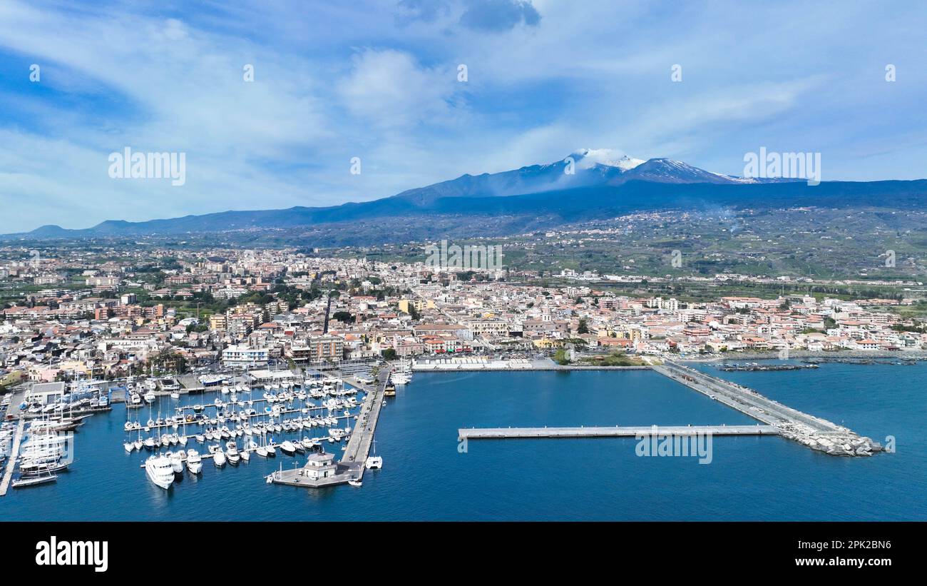 Destino de verano Riposto - vista aérea desde arriba en el puerto marítimo con barcos durante el día soleado con volcán Etna en el fondo con el mar Foto de stock