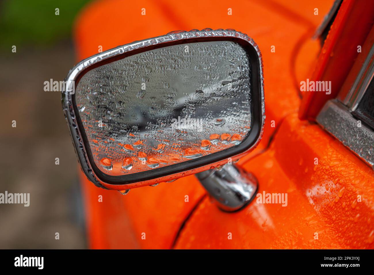 Espejo retrovisor de un coche retro naranja en el primer plano de la lluvia  Fotografía de stock - Alamy