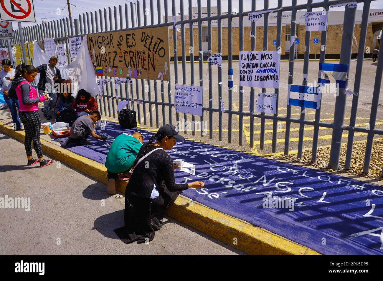 Migrantes y activistas asisten a una protesta en la que escriben los