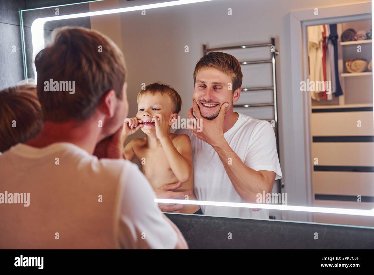 Mirando en el espejo en el baño. Padre e hijo están adentro en casa juntos  Fotografía de stock - Alamy