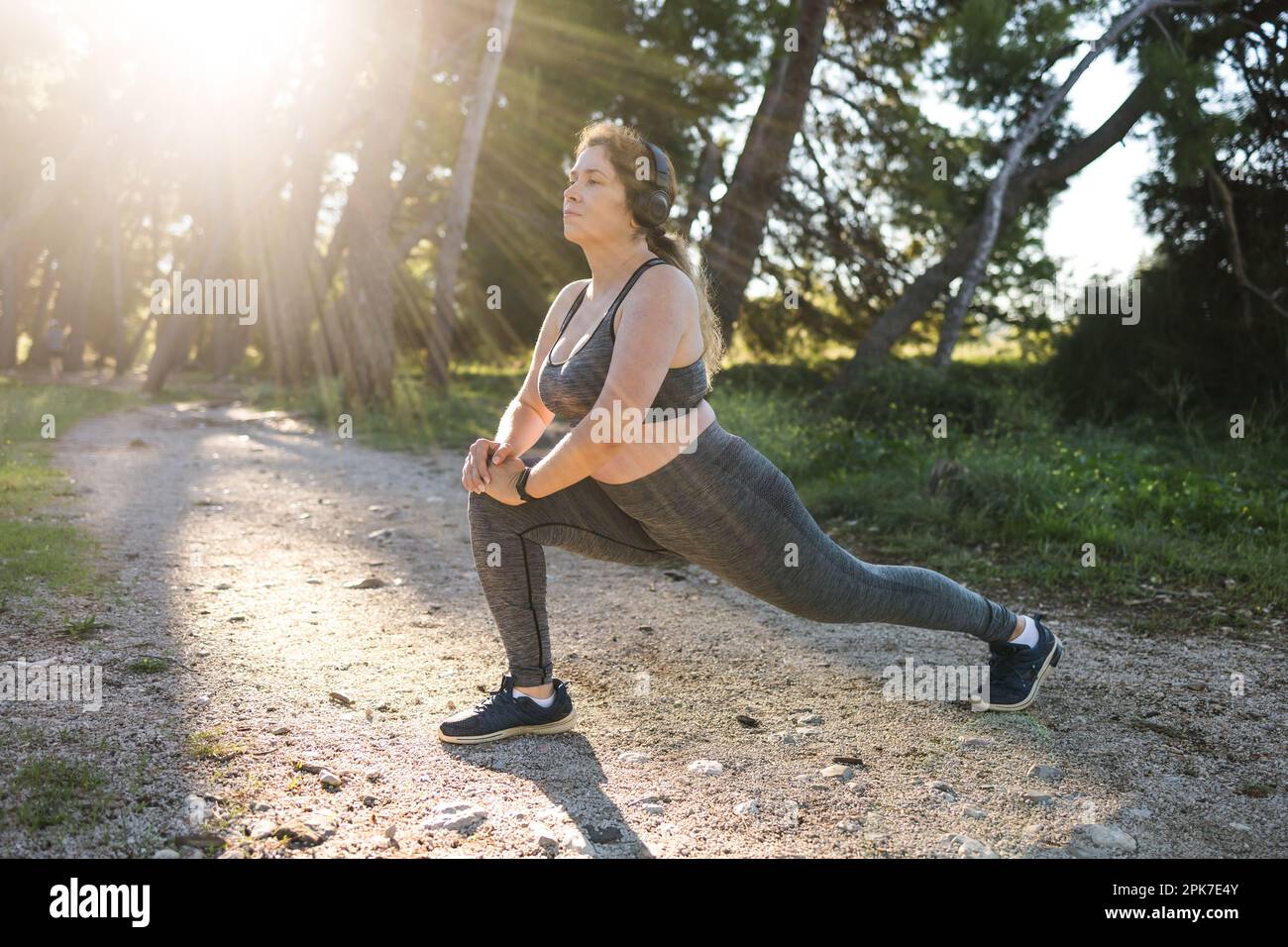 Joven bastante sonriente mujer de talla grande en top deportivo y polainas  haciendo deporte y escuchar música con auriculares en la mañana de verano  al aire libre Fotografía de stock - Alamy