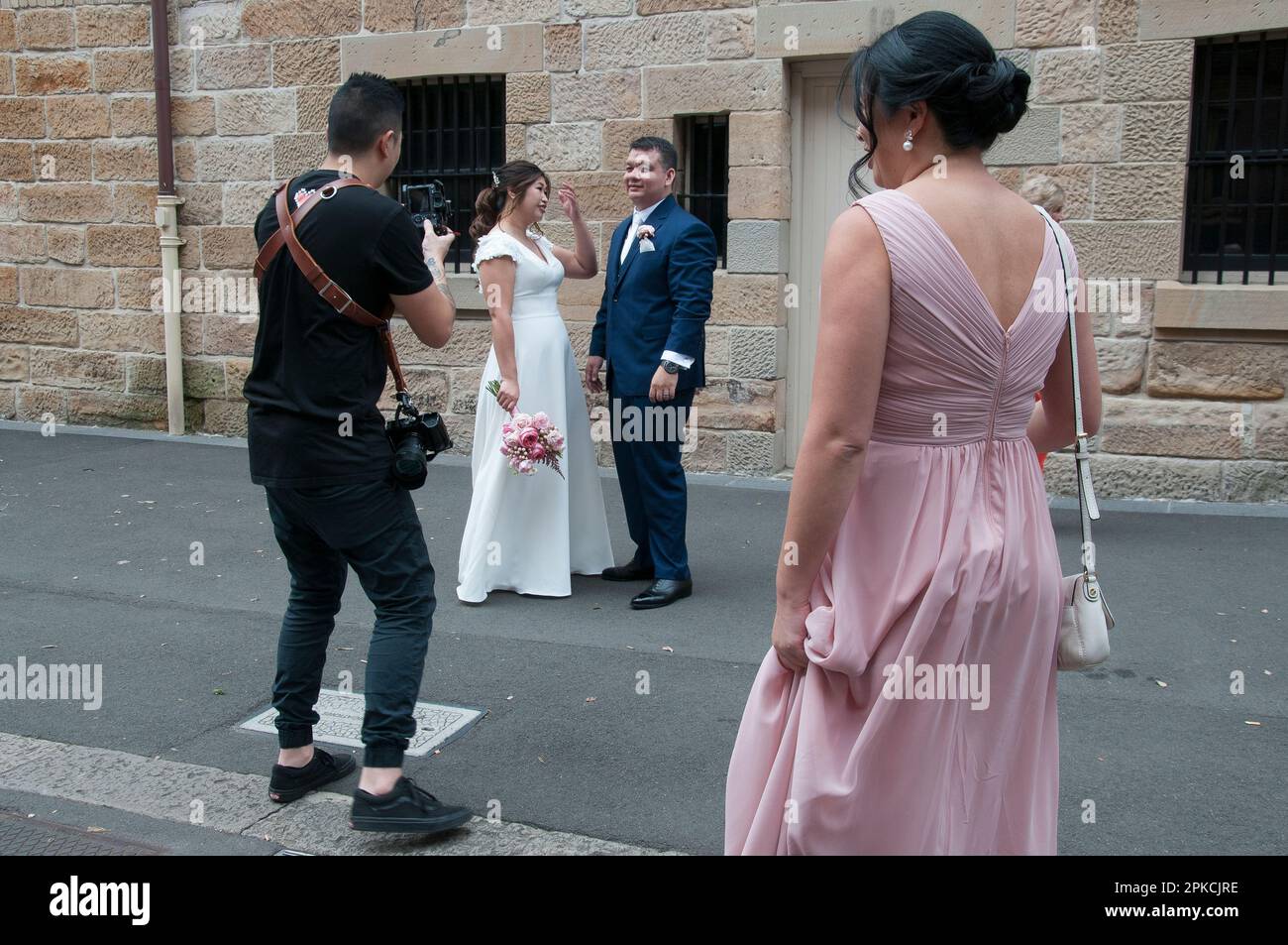 Organizadores de la industria de bodas gestionando una sesión de fotos para una pareja asiática, probablemente turistas extranjeros, en The Rocks, Sydney, Nueva Gales del Sur, Australia Foto de stock