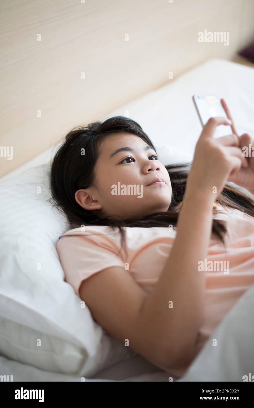 Chica acostada en la cama mirando su teléfono Fotografía de stock - Alamy