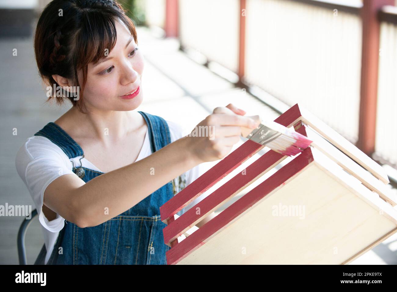 Mujer pintando una caja con un pincel Foto de stock